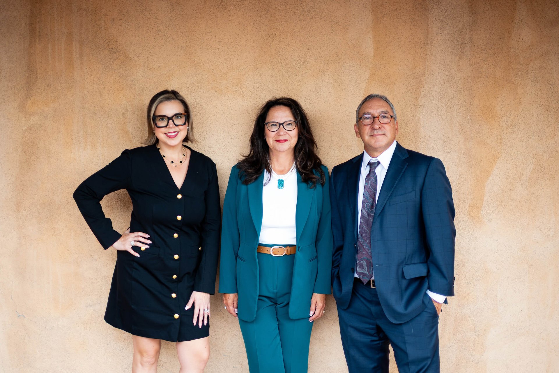 The attorneys of Peak Legal Group standing together against a New Mexico stucco wall